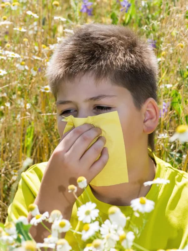 Niña con alergia al polen entre flores en primavera